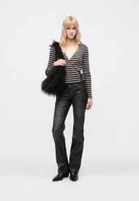 Sort stribet langærmet slå-om top med dyb v-hals, kombineret med mørke, flared jeans og en tekstureret sort faux pels håndtaske.