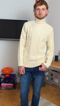 Krämfärgad stickad tröja med hög krage, med ett strukturerat diamantsmönster; matchas med blå denimjeans.