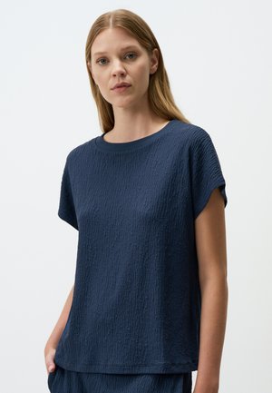 Top corto a maniche corte di colore blu navy con scollo rotondo, caratterizzato da una vestibilità leggermente ampia e un delicato motivo in rilievo su tutta la stoffa.