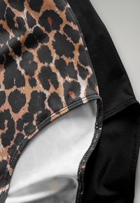 Costume da bagno con stampa leopardata caratterizzato da una combinazione di tonalità beige chiaro e nero, con un tessuto testurizzato, lati neri a contrasto e dettagli di cucitura puliti.