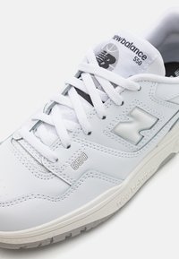 Weiße Leder-Sneaker mit strukturierten Akzenten, einer gepolsterten Zunge und Schnürsystem. Mit einem grauen New Balance-Logo und der Modellnummer 550.