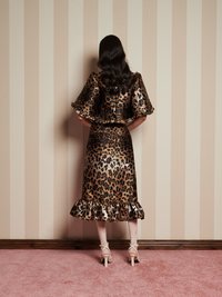 Satin obleka z leopardjim vzorcem in razširjenimi rokavi ter nabranim robom, ki ima sijajno teksturo, v kombinaciji z nude zapletenimi petami in ribjo mrežico.