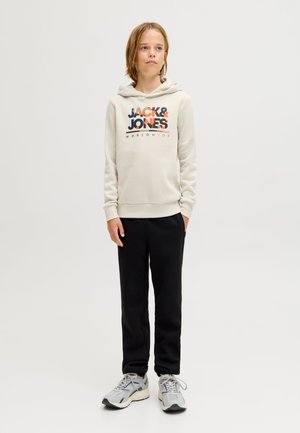 Lichtgrijze hoodie met "JACK & JONES" logo in marineblauw en oranje, gecombineerd met zwarte sweatpants en grijze hardloopschoenen.