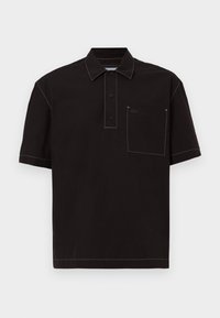 Polo de manga corta negro con cuello, tres botones, un bolsillo en el pecho y costuras blancas en contraste. Logo de Lacoste en el bolsillo.
