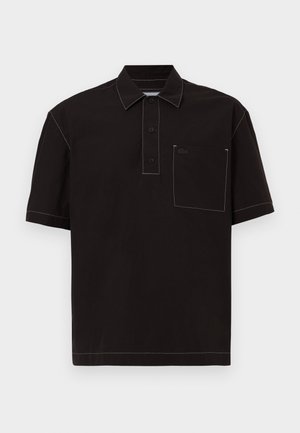 Polo shirt nero a maniche corte con colletto, tre bottoni, una tasca sul petto e cuciture bianche a contrasto. Logo Lacoste sulla tasca.