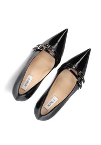 Zwarte gepatineerde lederen ballerina's met een puntige neus en twee gouden gesps op de band. Gladde textuur met een neutrale beige binnenzool en zichtbare branding.