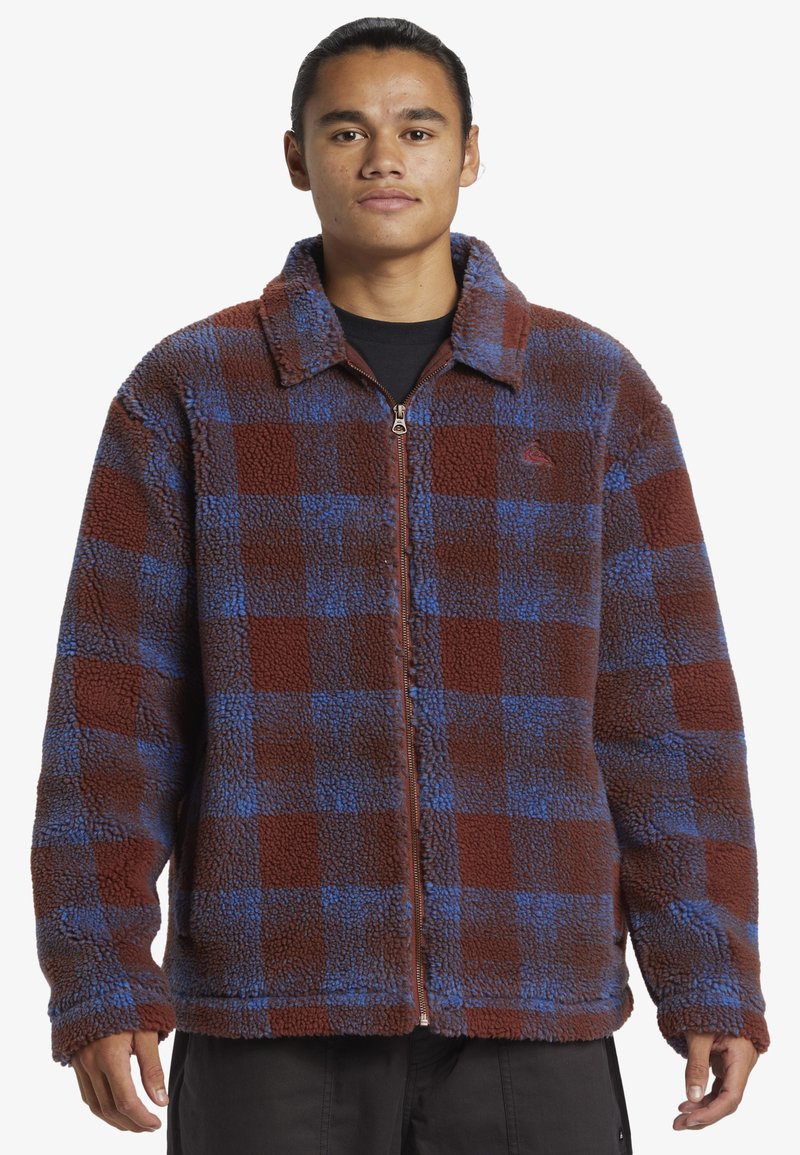 Veste en polaire à motif vichy marron et bleu, dotée d'une fermeture éclair à l'avant, d'un col pointu et d'un tissu texturé pour la chaleur.