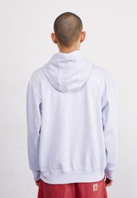Felpa viola chiaro con cappuccio regolabile, polsini e orlo a costine. Caratterizzata da un piccolo logo bianco sul retro, vicino al collo. Tessuto morbido.