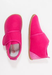 Różowe materiałowe buty o mi ękkiej, elastycznej konstrukcji, z rzepem, gumową podeszwą i teksturowanym uchwytem wzdłuż krawędzi.