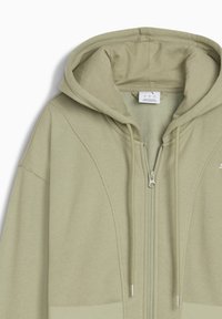 Lichtgroene hoodie met een kangoeroenzak, ritsluiting, trekkoord capuchon en zachte stof. Beschikt over een gladde textuur en geribbelde accenten.