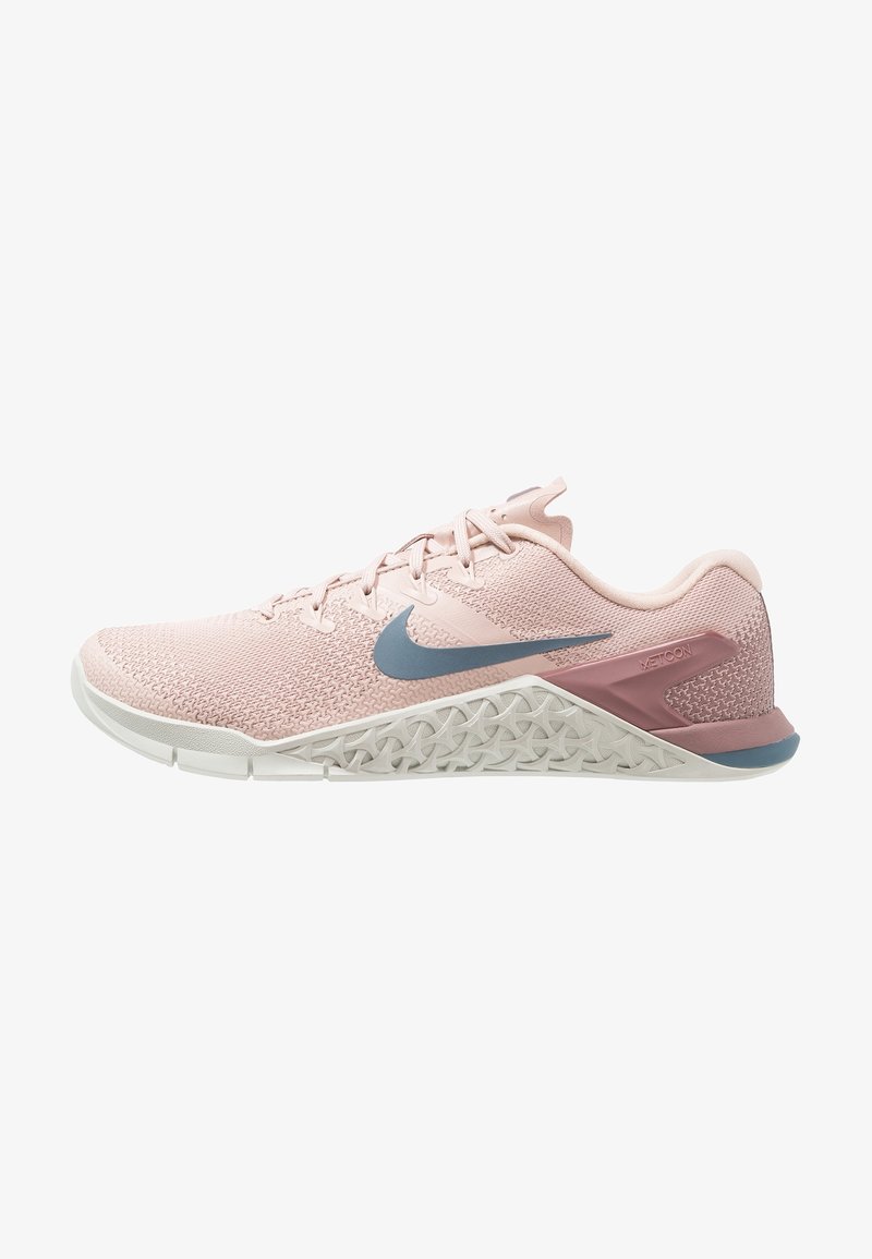 Zapatilla deportiva de color rosa claro con una parte superior de tejido transpirable, detalles en gris y una suela blanca texturizada que presenta un patrón geométrico único.