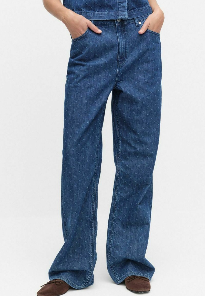 Blå denimjeans med en utställd design, som har subtila texturmönster och framfickor. Tyget är mjukt med en klassisk finish.