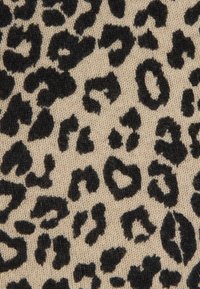Υφασμα με λεοπάρ σχέδιο που παρουσιάζει μαύρες κηλίδες σε μπεζ φόντο, με υφή πλεκτού, τονίζοντας διακριτά σχήματα μοτίβου.
