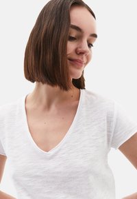 Witte, lichtgewicht T-shirt met een V-hals en korte mouwen, gemaakt van een zachte, licht gestructureerde stof.