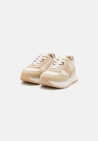 Sneakers atletici beige con tomaia in pelle liscia, dettagli color crema, lacci classici e suola in gomma testurizzata per una buona aderenza. Dettaglio del logo dorato sul lato.