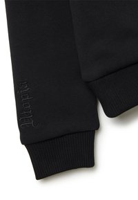 Dettaglio di una felpa nera con polsini a costine, texture morbida e logo ricamato discreto sul polsino, che mette in mostra un design minimalista.