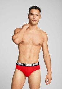 Rote Unterhose mit schwarzem Gummibund, auf dem "PUMA" in weißer Schrift steht. Glattes Material, enganliegendes Design, mit vorderem Stützpaneel.