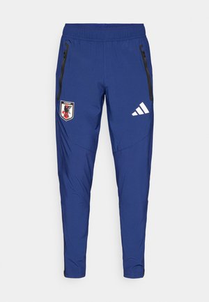 Pantalones deportivos azules hechos de material ligero, con un bolsillo con cremallera negra, logo de la Asociación de Fútbol de Japón y franjas blancas de Adidas.