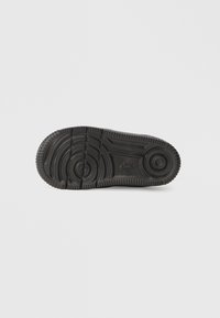 Suola di sneaker nera in gomma con scanalature testurizzate e motivi circolari. Presenta un logo Nike impresso nella zona del tallone.