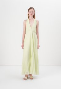 Abito maxi a pieghe verde chiaro con scollatura a V profonda e gonna fluente. Tessuto morbido, design senza maniche e leggero luccichio.