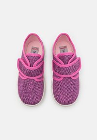 Sapatos de tecido rosa com superfície texturizada, apresentando duas tiras ajustáveis de Velcro e uma sola de borracha branca.