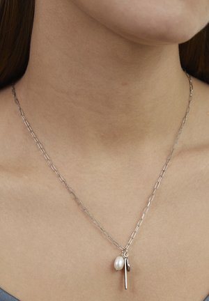 Silver chain necklace with an organic pearl charm and a metal pendant. The chain features elongated links and a simple, modern design.