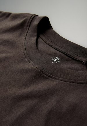 Braunes Baumwoll-T-Shirt mit rundem Halsausschnitt und kurzen Ärmeln. Merkmale ein Etikett mit der Aufschrift "THE SET" in Weiß am inneren Kragen.