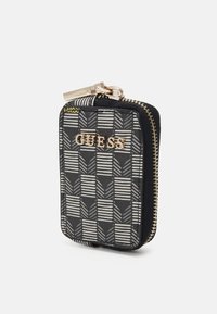 Portefeuille zippé noir et gris à motifs avec logo "GUESS" doré et tirette de fermeture éclair dorée, debout sur fond blanc.