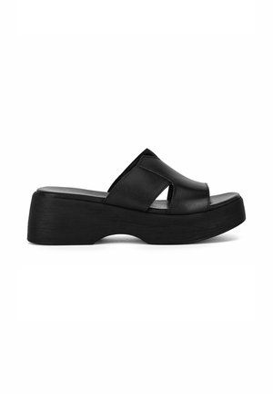 Sandalo slide platform nero con suola spessa e parte superiore in pelle larga, con punta aperta e dettagli ritagliati ai lati.