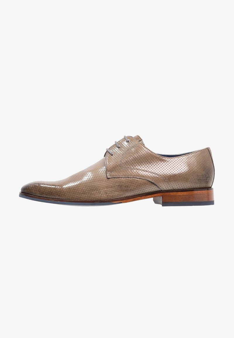 Chaussure habillée en cuir marron perforé avec trois œillets, semelle en bois et petit talon, orientée vers la droite sur fond blanc.