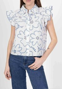 Chemise blanche à manches courtes avec imprimé floral bleu et détails froncés aux épaules. Dotée de boutons sur le devant et d'un col rabattu.