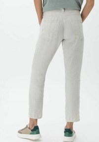 Ljusgrå linnbyxor med en avsmalnande form, med två bakfickor och en ren finish. Matchas med beige och gröna sneakers.