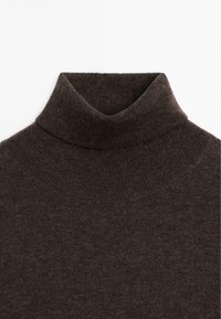 Brown turtleneck sweater featuring a soft, fine-knit texture. The collar is neatly folded, and the material appears warm and comfortable.