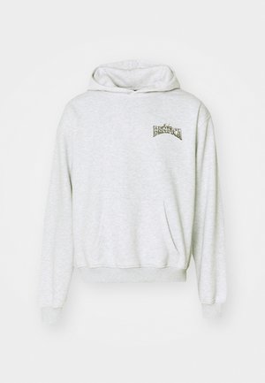 Lichtgrijze sweatshirt met capuchon, voorzak en geribbelde manchetten. Heeft een bedrukte "Benfica" logo in donkere letters op de borst.