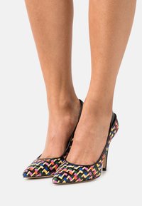 Escarpins tissés à talons hauts avec un bout pointu, arborant un motif multicolore de rose, jaune et bleu sur un fond noir.