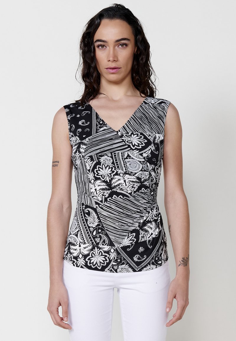Top fără mâneci alb-negru, cu decolteu în V, având un amestec de modele paisley și florale, cu linii unghiulare și textură plisată.
