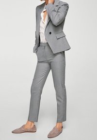 Completo con blazer a quadri grigia e pantaloni abbinati, caratterizzato da una vestibilità sartoriale, chiusura con un bottone e tessuto liscio con una texture sottile.