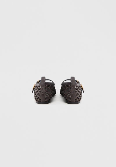 Open-back sandalen met een geweven donkerbruin synthetisch materiaal, platte hak en hardware-accenten in goudtint. Gestructureerd oppervlak met uitsparingen.