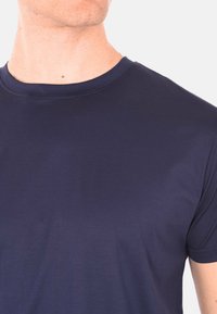 T-shirt a girocollo blu navy realizzato in tessuto morbido e liscio. Maniche corte con una vestibilità aderente, che mostra dettagli di cucitura discreti nel colletto.