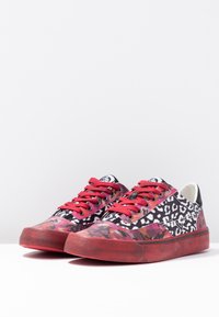 Baskets en toile avec un imprimé léopard noir et blanc agrémenté de motifs abstraits roses et rouges. Des lacets rouges et des semelles en caoutchouc complètent le design.