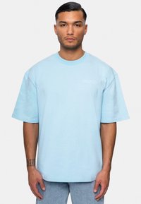 Lyseblå oversized t-shirt, kortærmet, rund hals, lavet af bomuld. Har et diskret broderet "DROPSIZE" logo på venstre bryst.