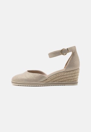 Beige wedge espadrille with a rounded toe, suede-like upper, ankle strap with a gold buckle, and woven jute detailing on the heel.