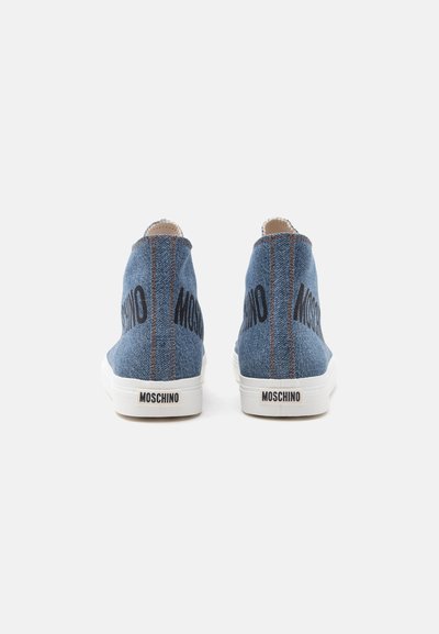 Ζευγάρι τακούνια από denim με ορατές ραφές, μαύρο λογότυπο "MOSCHINO" στη φτέρνα και λευκές λαστιχένιες σόλες.