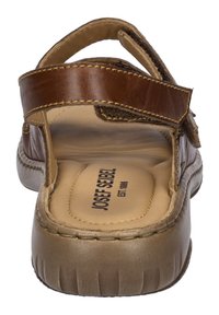 Bruine leren sandaal met een brede strap met klittenbandsluiting, stevige zool en geplofte binnenzool met merklogo.