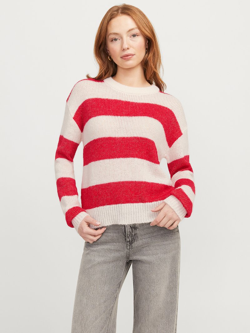 Pull à rayures rouges et blanches avec une coupe décontractée, texture tricotée, col rond et manches longues, associé à un jean gris clair.