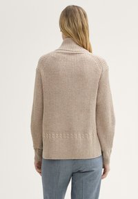 Beżowy sweter dziany z wysokim kołnierzem, z teksturowanymi wzorami i ribbingowymi akcentami przy mankietach i u dołu. Wyświetlony widok z tyłu.