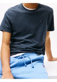 Námořnická modrá bavlněná tričko s krátkými rukávy a kulatým výstřihem, s malým bílým, červeným a modrým logem na hrudi, doplněné světle modrými tepláky.