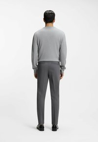 Gray sweater and tailored gray trousers from the back. The sweater has long sleeves, and the trousers feature a slim fit with a smooth texture.