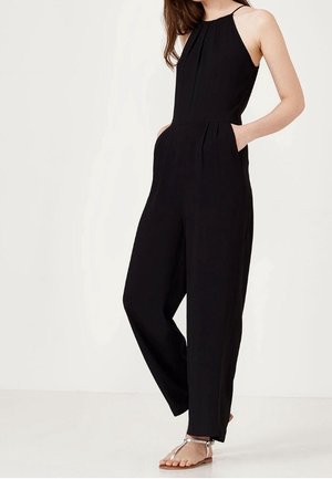 Mono negro sin mangas con un torso ajustado, perneras anchas, bolsillos laterales y una textura suave. Diseño sencillo, sin patrones visibles ni herrajes.