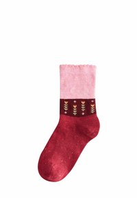 Rote und rosa gestrickte Socke mit einem gerippten oberen Teil, floralen Mustern auf einem dunklen Band und subtilen Sprenkeln im gesamten Sockenkörper.